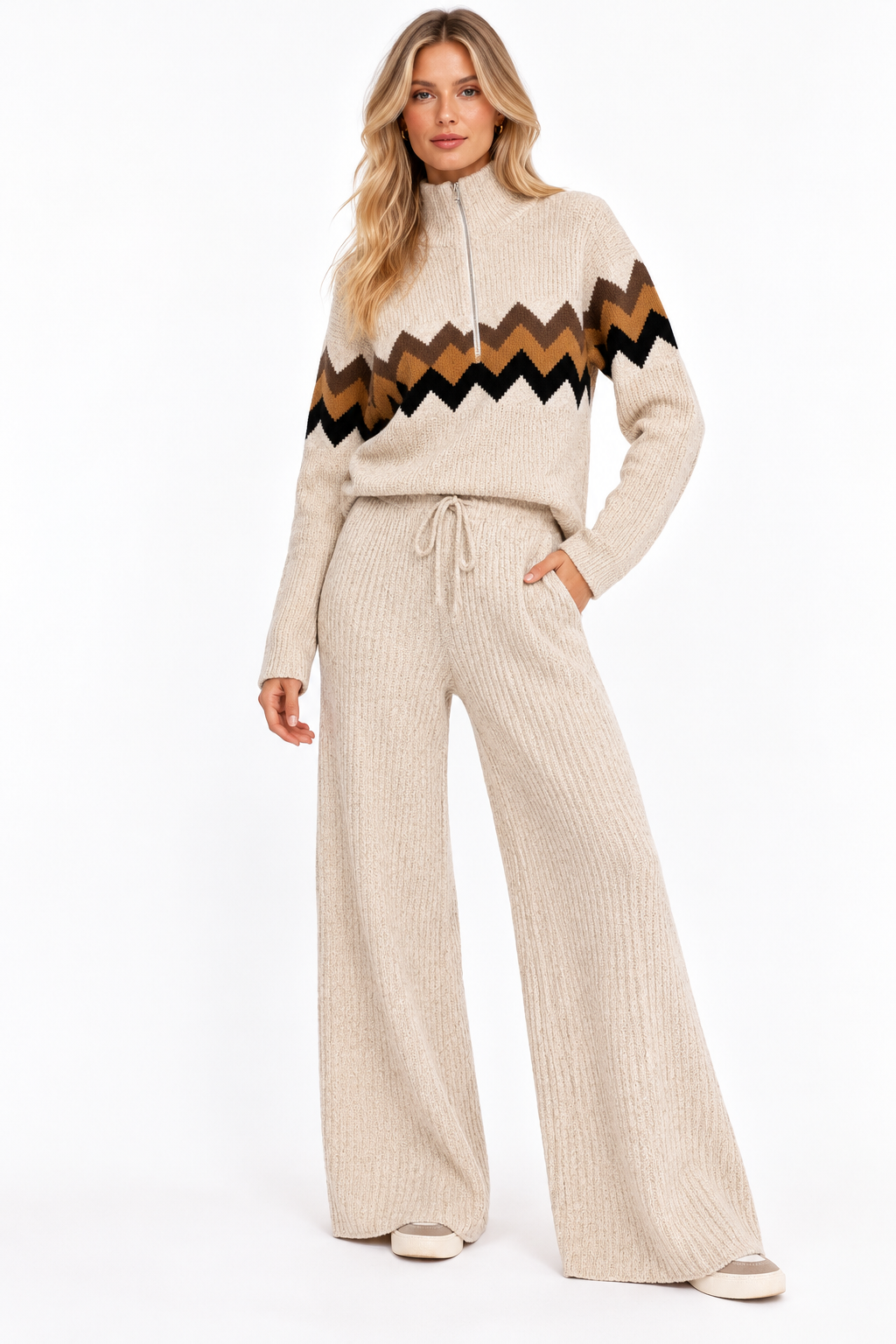 A woman modeling a beige knit two-piece set featuring a mock-neck long-sleeve sweater with a brown, black, and beige chevron pattern across the chest, paired with matching wide-leg ribbed pants.